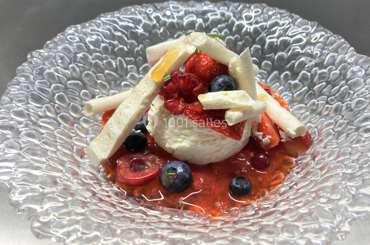 Dessert composé de fruits rouges, myrtilles, meringues et crème, présenté dans une assiette en verre texturée.