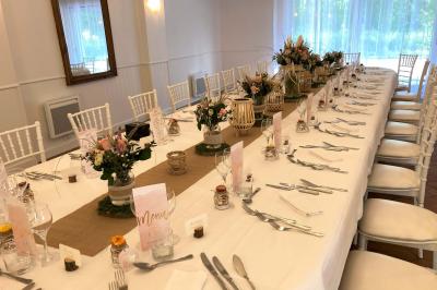 Homme concentré cuisinant en extérieur sur une plancha, entouré de végétation sous un ciel nuageux.