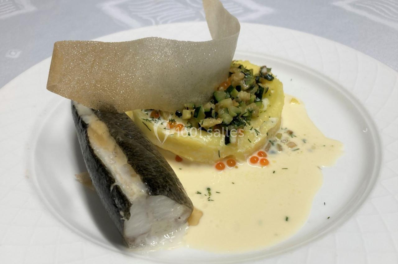 Filet de poisson accompagné d'une purée garnie de légumes, d'œufs de poisson et d'une sauce crémeuse, sur assiette blanche.