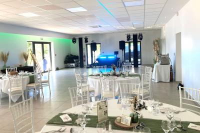 Homme concentré cuisinant en extérieur sur une plancha, entouré de végétation sous un ciel nuageux.