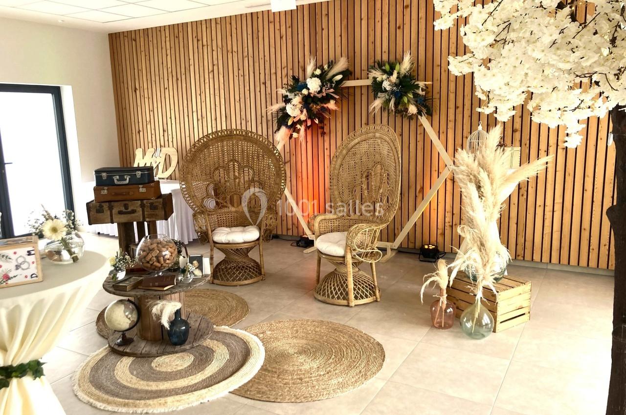 Décoration intérieure avec fauteuils en rotin, tapis en jute, fleurs séchées et éléments vintage dans une pièce boisée.