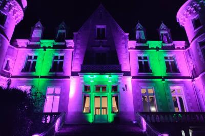Un DJ mixe dans une salle éclairée par des lumières colorées, avec des tables hautes et un décor sobre.