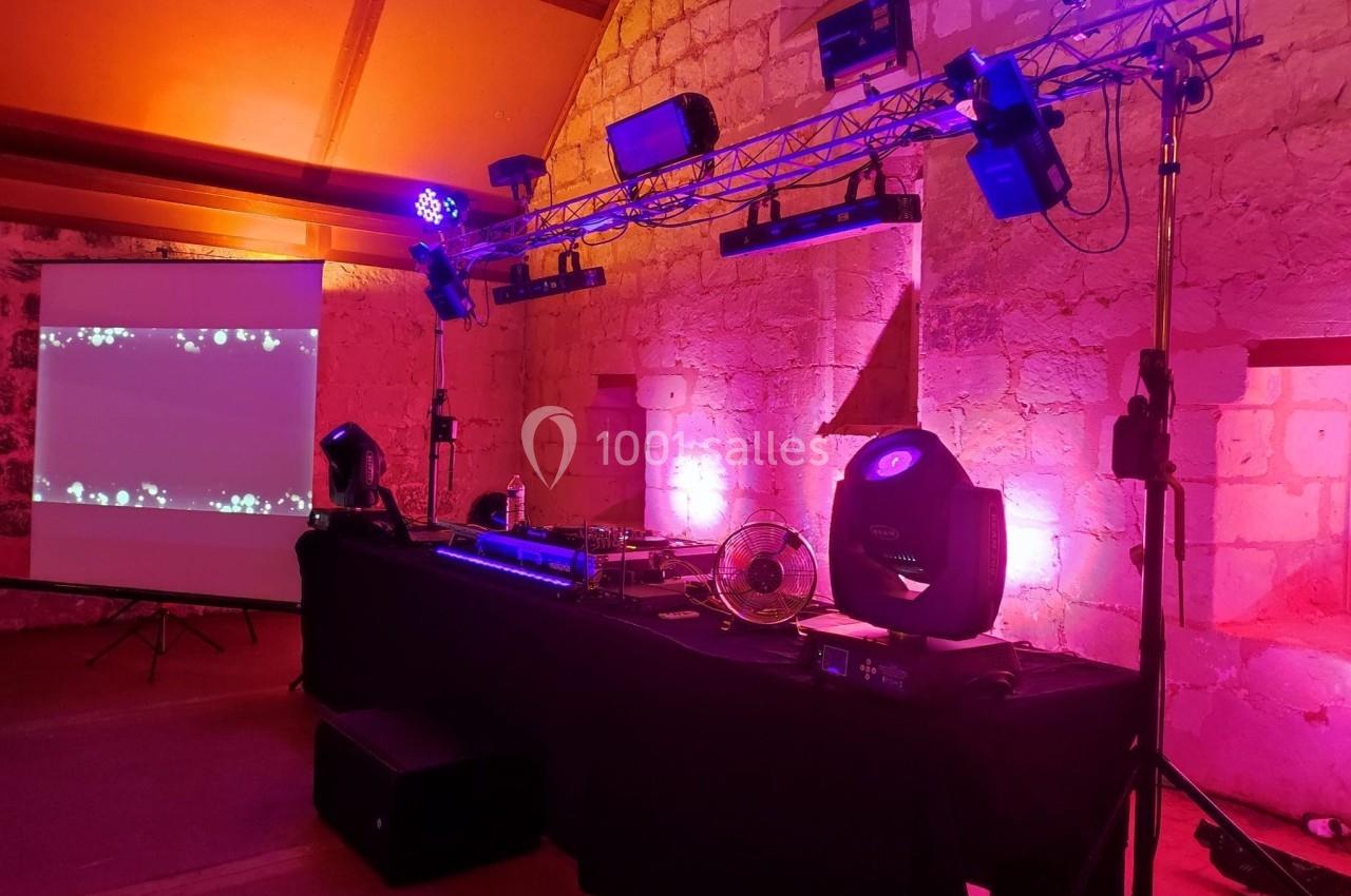 Installation de matériel de sonorisation et d'éclairage avec projecteurs colorés dans une salle en pierre.