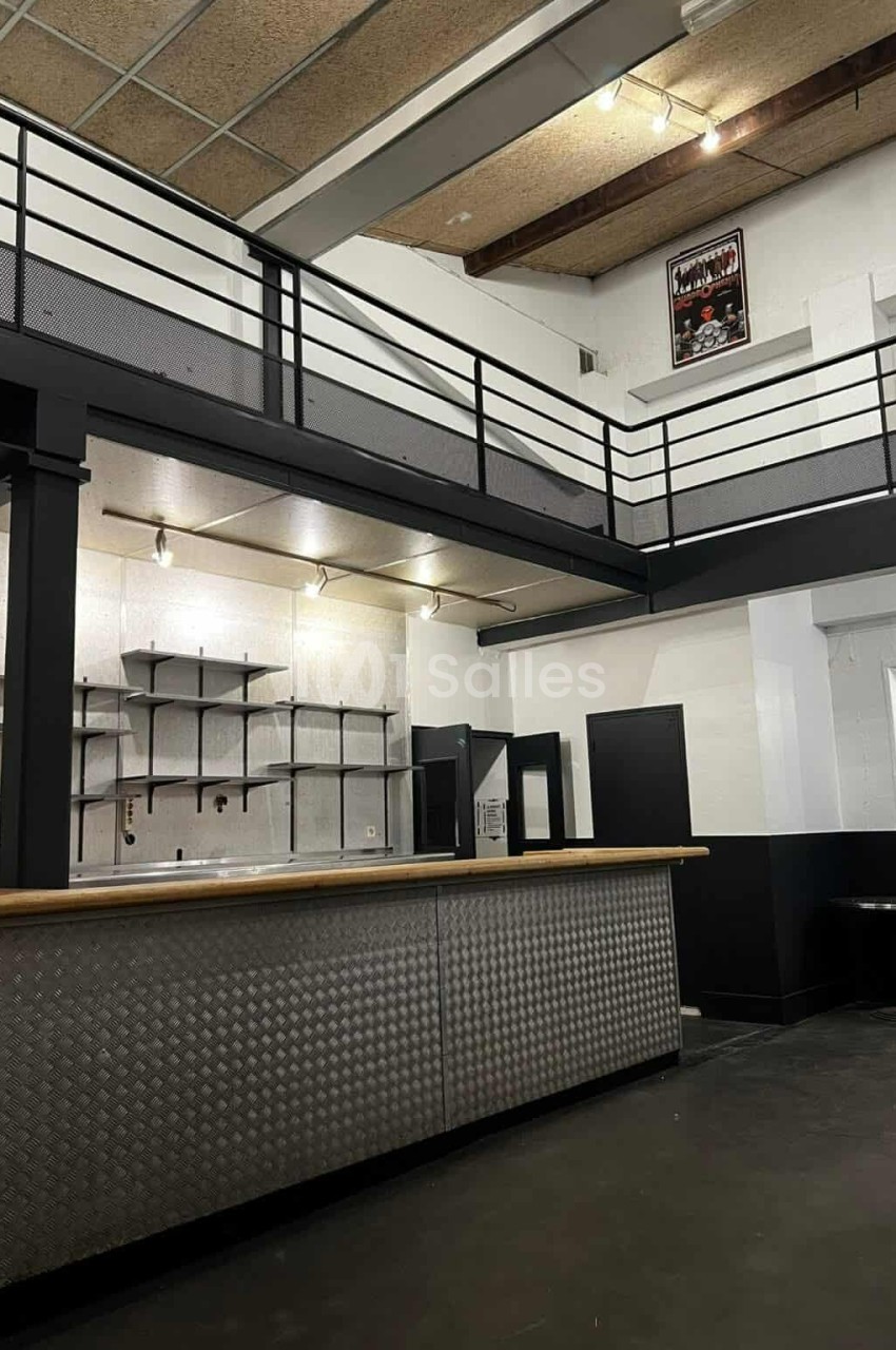 Intérieur d'un espace industriel avec un comptoir métallique, une mezzanine et des étagères murales.