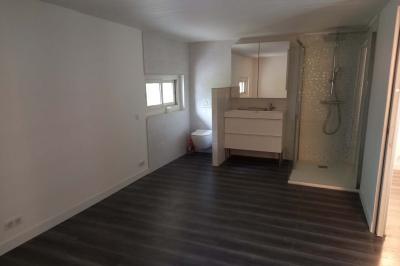 Salle lumineuse avec une grande table dressée pour un repas, décorée de fleurs blanches et rouges, entourée de chaises…