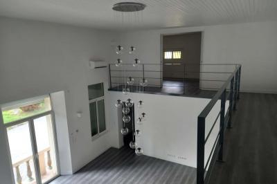 Salle lumineuse avec une grande table dressée pour un repas, décorée de fleurs blanches et rouges, entourée de chaises…