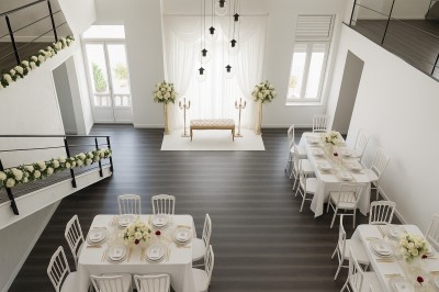 Salle lumineuse avec une grande table dressée pour un repas, décorée de fleurs blanches et rouges, entourée de chaises…