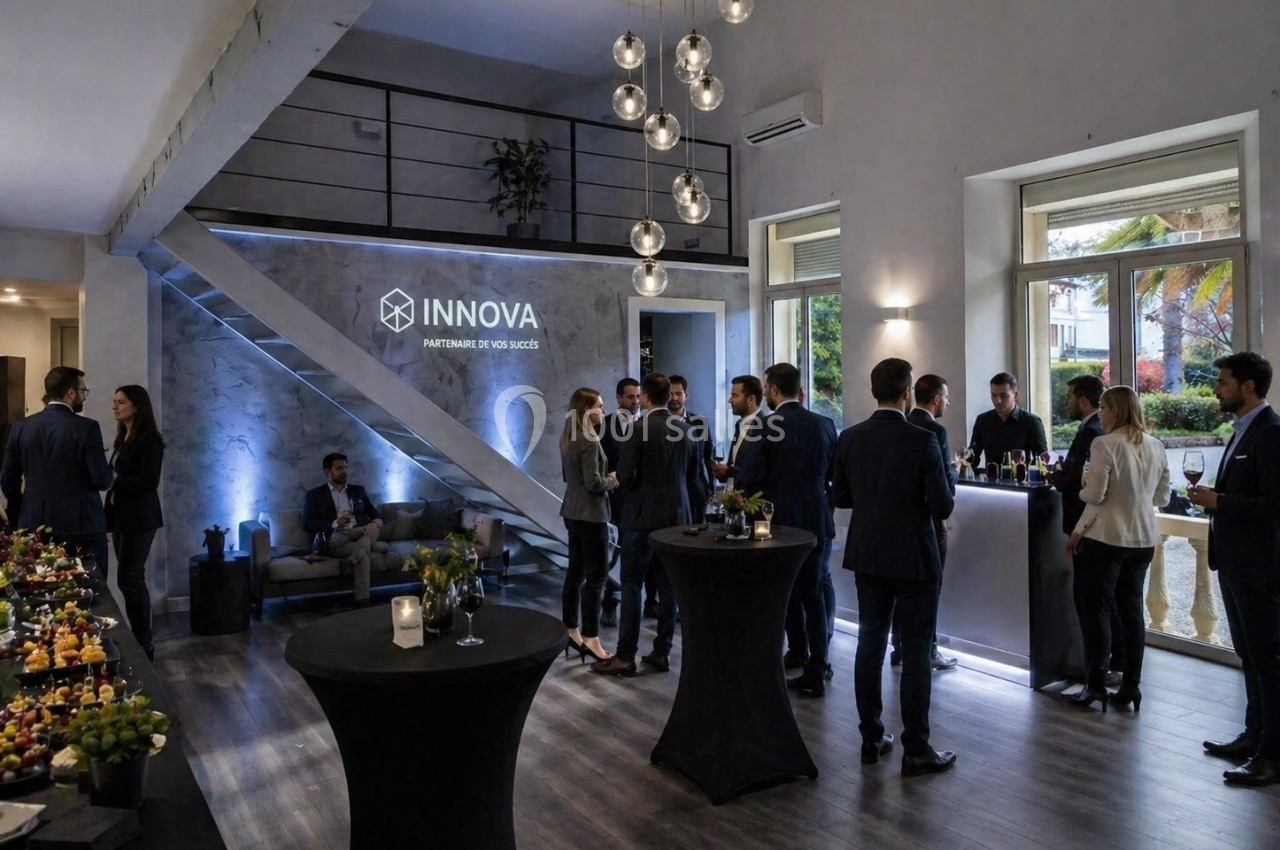 Groupe de personnes en tenue professionnelle discutant lors d'un événement dans un espace moderne avec buffet et éclairage…