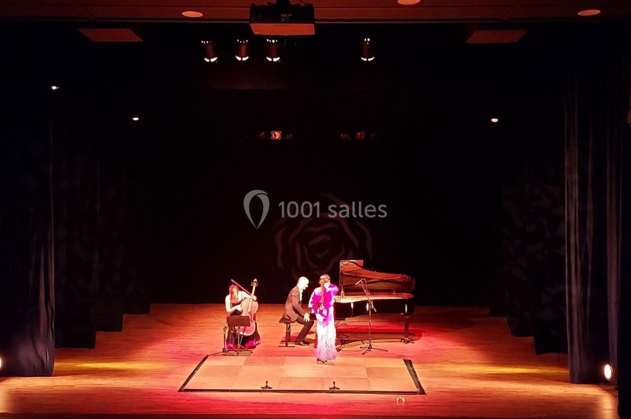 Deux musiciens jouant du piano et du violoncelle accompagnent une chanteuse sur une scène éclairée.