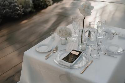 Miniature Votristoire #3 Table en bois longue dressée en extérieur, ornée de fleurs, citrons et vaisselle, entourée d'arbres et de verdure.