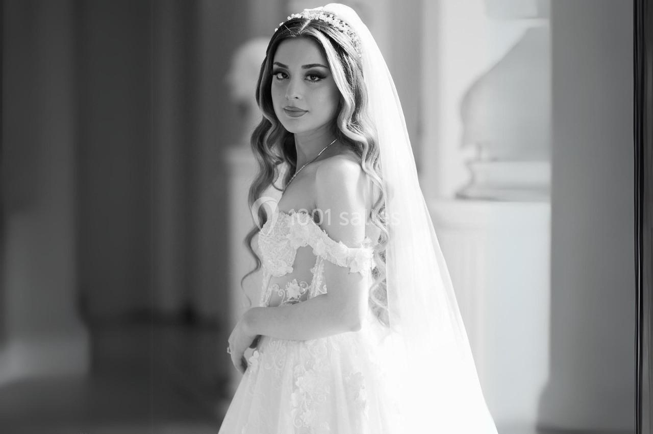 Femme en robe de mariée avec voile, posant dans un intérieur lumineux et élégant.