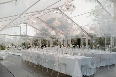 Miniature Votristoire #18 Table en bois longue dressée en extérieur, ornée de fleurs, citrons et vaisselle, entourée d'arbres et de verdure.