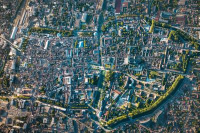 Femme de dos dans une chambre mansardée avec poutres apparentes, lit, télévision et baignoire en arrière-plan.