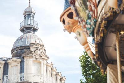 Femme de dos dans une chambre mansardée avec poutres apparentes, lit, télévision et baignoire en arrière-plan.
