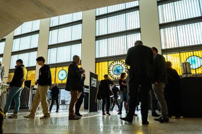 Femme de dos dans une chambre mansardée avec poutres apparentes, lit, télévision et baignoire en arrière-plan.