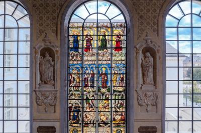 Femme de dos dans une chambre mansardée avec poutres apparentes, lit, télévision et baignoire en arrière-plan.