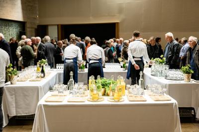 Femme de dos dans une chambre mansardée avec poutres apparentes, lit, télévision et baignoire en arrière-plan.