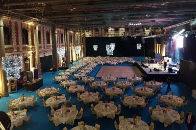 Femme de dos dans une chambre mansardée avec poutres apparentes, lit, télévision et baignoire en arrière-plan.