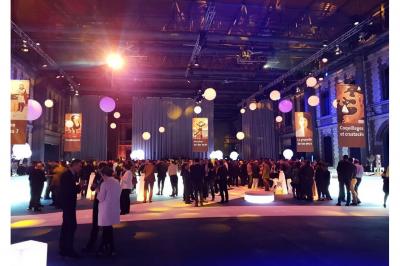 Femme de dos dans une chambre mansardée avec poutres apparentes, lit, télévision et baignoire en arrière-plan.
