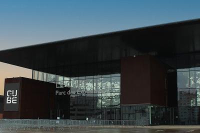 Femme de dos dans une chambre mansardée avec poutres apparentes, lit, télévision et baignoire en arrière-plan.