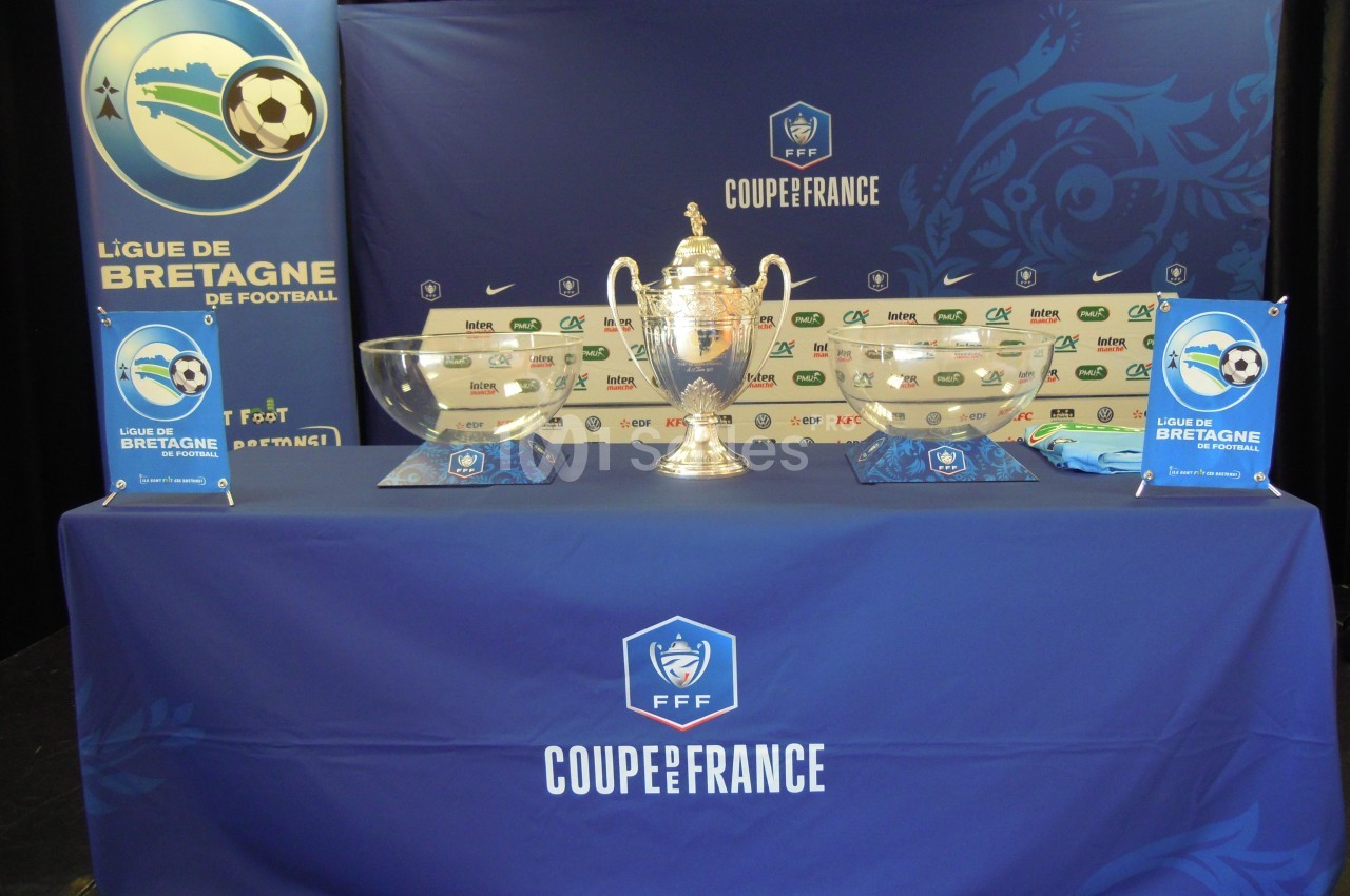 Trophée de la Coupe de France exposé sur une table ornée de logos de la Ligue de Bretagne et de sponsors.