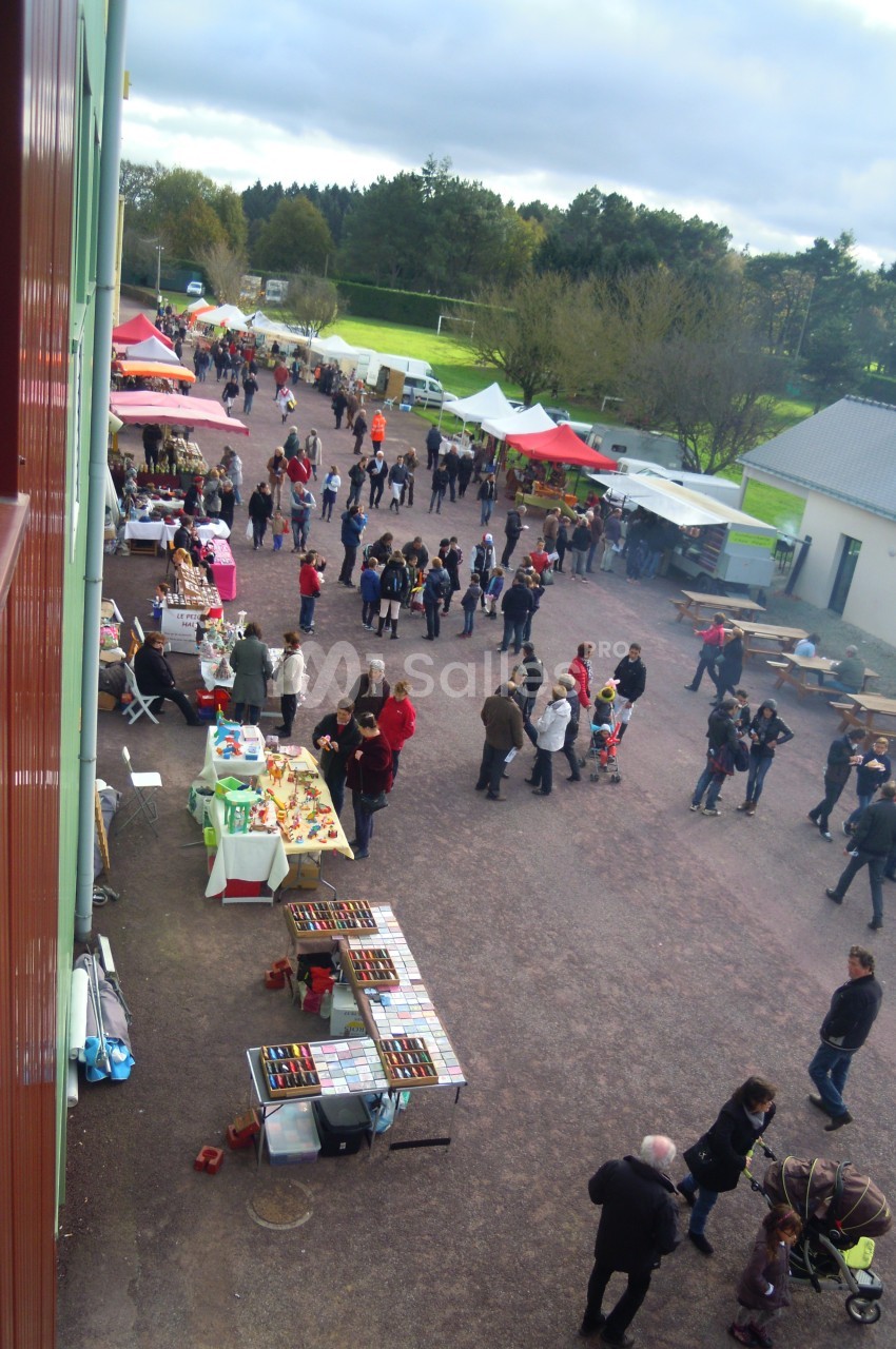 Vue aérienne d'un marché en plein air avec des stands colorés et des visiteurs se déplaçant entre les étals.