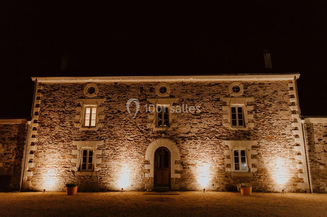 Façade en pierre d'un bâtiment ancien éclairé par des lumières chaudes, de nuit.