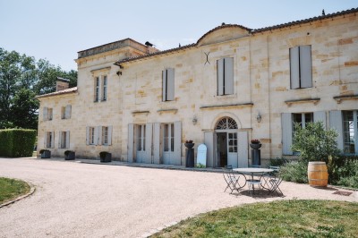 Miniature Location salle Arveyres (Gironde) - Château Larteau #73 Façade d'une grande maison en pierre claire avec volets bleus, entourée d'un jardin et d'une allée gravillonnée.