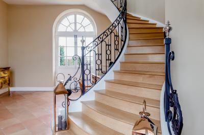Vue d'un jardin verdoyant avec un arbre central, un escalier en pierre et un lac au coucher du soleil.