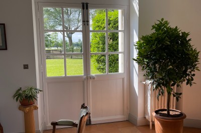 Vue d'un jardin verdoyant avec un arbre central, un escalier en pierre et un lac au coucher du soleil.