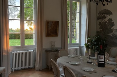 Vue d'un jardin verdoyant avec un arbre central, un escalier en pierre et un lac au coucher du soleil.