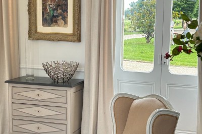 Vue d'un jardin verdoyant avec un arbre central, un escalier en pierre et un lac au coucher du soleil.