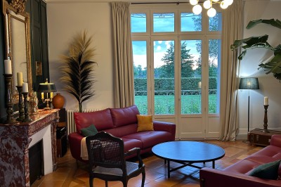 Vue d'un jardin verdoyant avec un arbre central, un escalier en pierre et un lac au coucher du soleil.