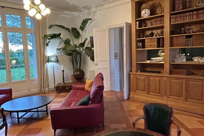 Vue d'un jardin verdoyant avec un arbre central, un escalier en pierre et un lac au coucher du soleil.