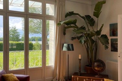 Vue d'un jardin verdoyant avec un arbre central, un escalier en pierre et un lac au coucher du soleil.