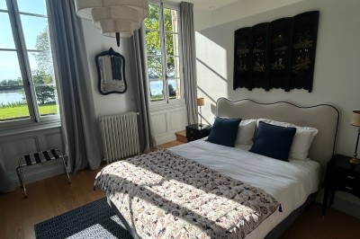 Vue d'un jardin verdoyant avec un arbre central, un escalier en pierre et un lac au coucher du soleil.