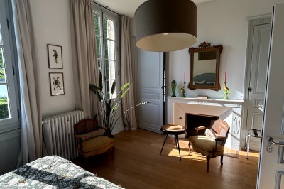 Vue d'un jardin verdoyant avec un arbre central, un escalier en pierre et un lac au coucher du soleil.