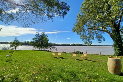 Vue d'un jardin verdoyant avec un arbre central, un escalier en pierre et un lac au coucher du soleil.