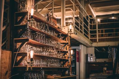 Un chandelier allumé éclaire des livres anciens posés sur un pupitre en bois, devant une fresque sombre et colorée.