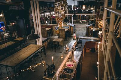 Un chandelier allumé éclaire des livres anciens posés sur un pupitre en bois, devant une fresque sombre et colorée.