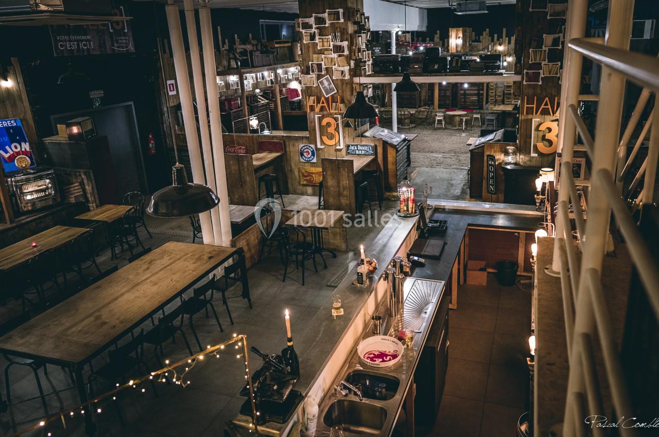 Vue d'un espace intérieur industriel avec tables en bois, comptoir, éclairage tamisé et décoration vintage.