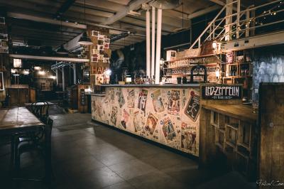 Un chandelier allumé éclaire des livres anciens posés sur un pupitre en bois, devant une fresque sombre et colorée.
