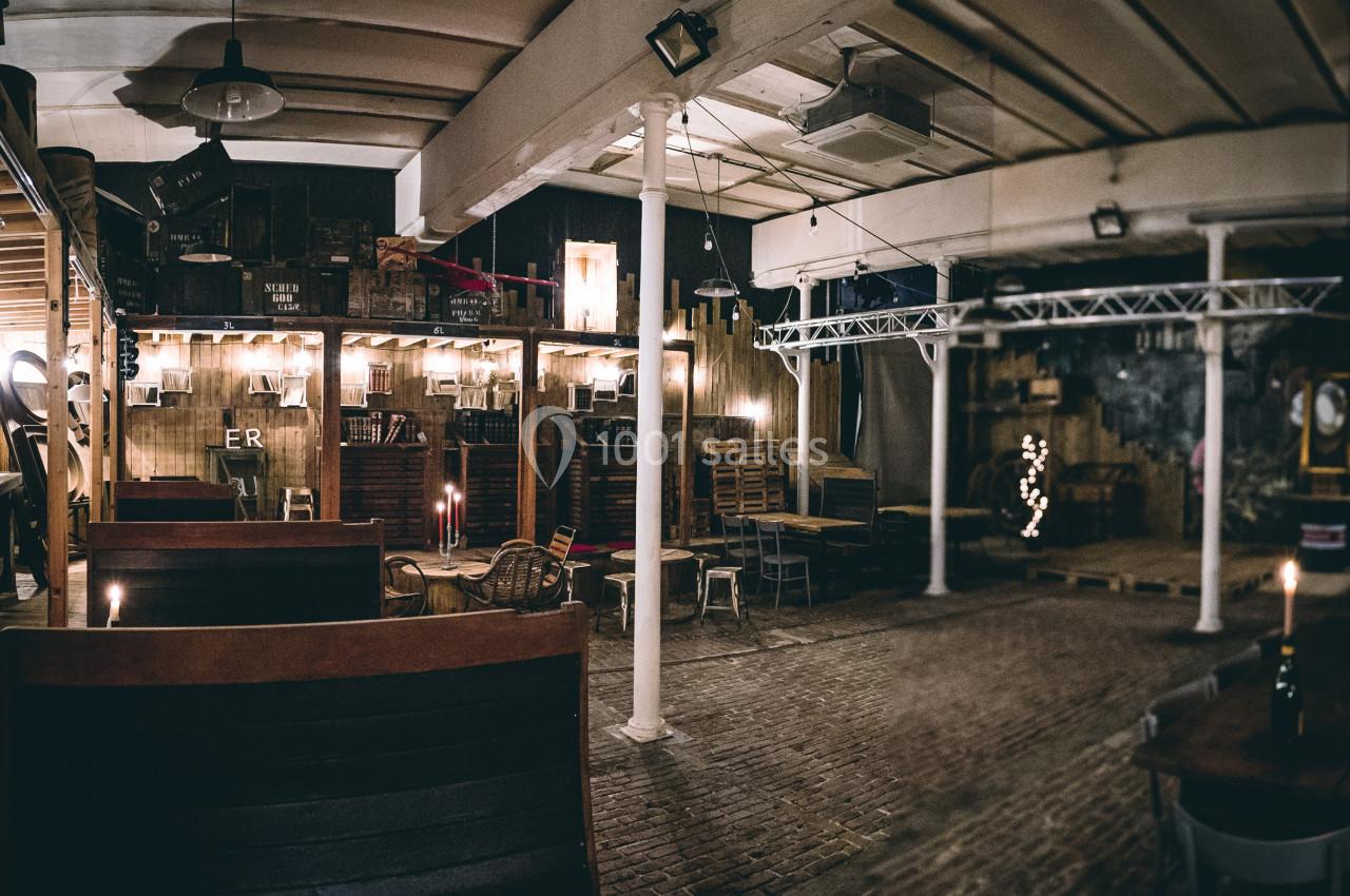Intérieur d'un espace aménagé avec des tables en bois, éclairage tamisé et décor industriel.