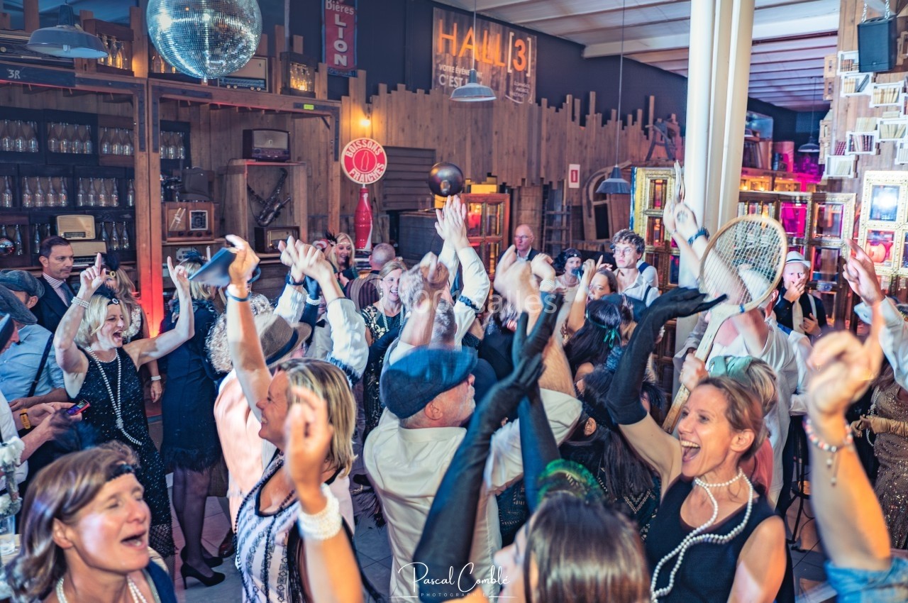 Groupe de personnes dansant et célébrant dans une ambiance festive avec une décoration rétro.