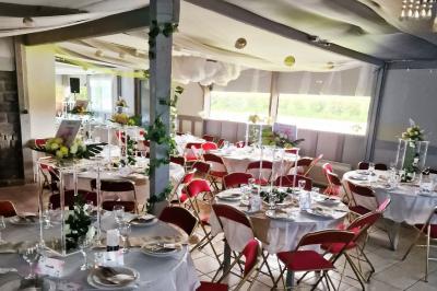 Deux tables rondes décorées pour un événement, avec nappes blanches, fleurs, verres et serviettes pliées.