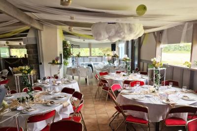 Deux tables rondes décorées pour un événement, avec nappes blanches, fleurs, verres et serviettes pliées.