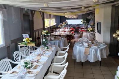Deux tables rondes décorées pour un événement, avec nappes blanches, fleurs, verres et serviettes pliées.