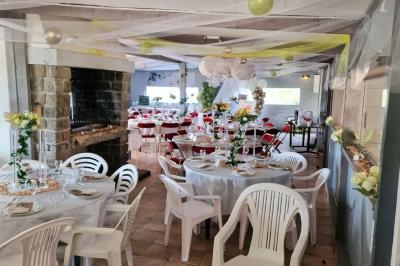 Deux tables rondes décorées pour un événement, avec nappes blanches, fleurs, verres et serviettes pliées.