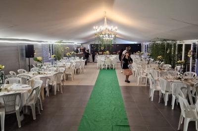 Deux tables rondes décorées pour un événement, avec nappes blanches, fleurs, verres et serviettes pliées.