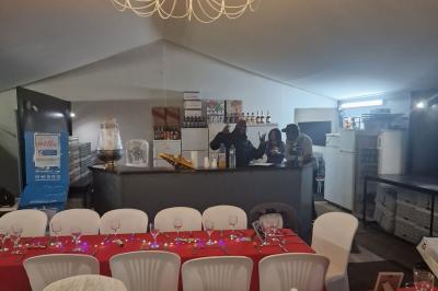 Deux tables rondes décorées pour un événement, avec nappes blanches, fleurs, verres et serviettes pliées.